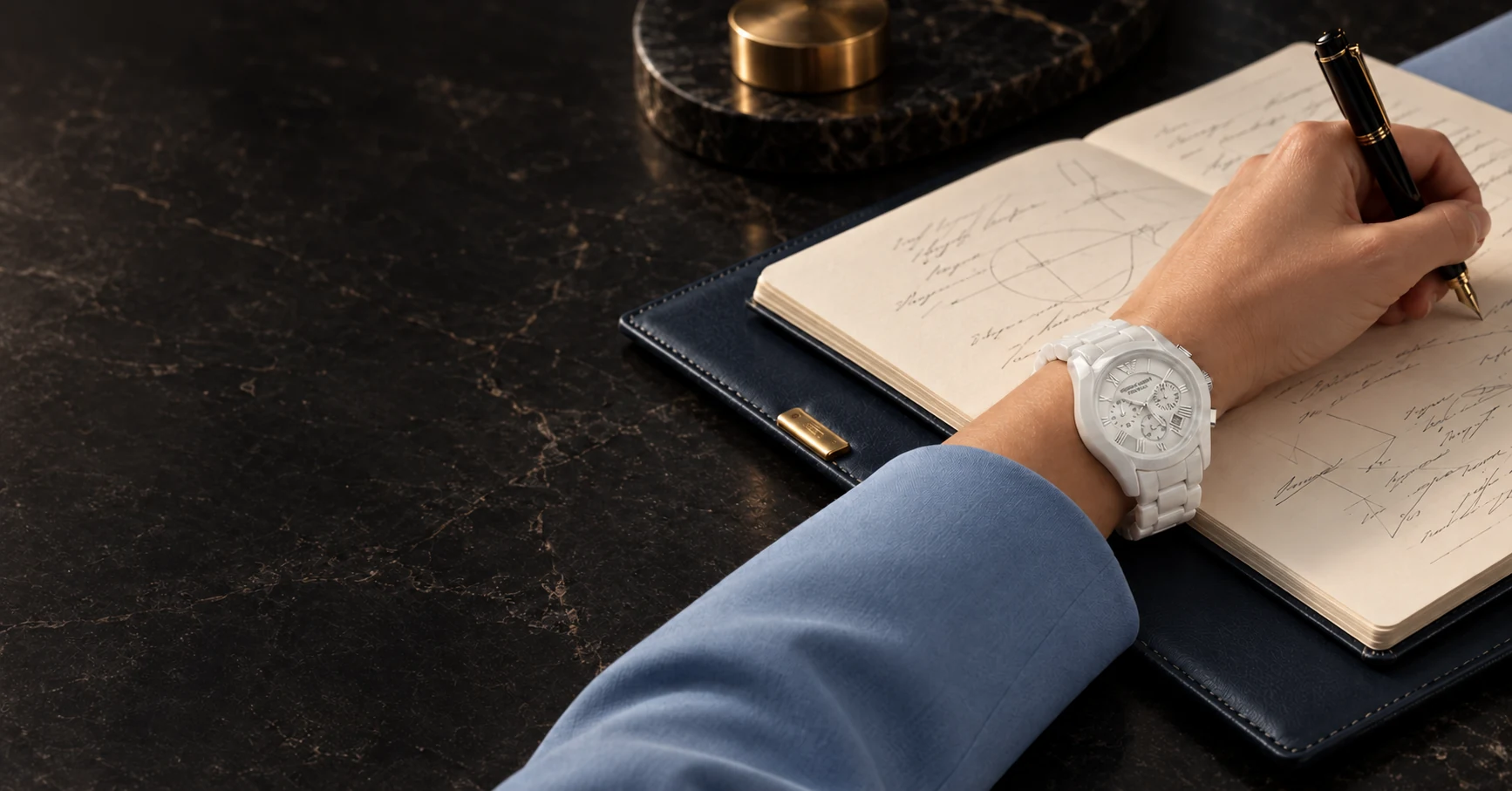 A notebook, fountain pen and blue sleeve arranged on a stone writing table.